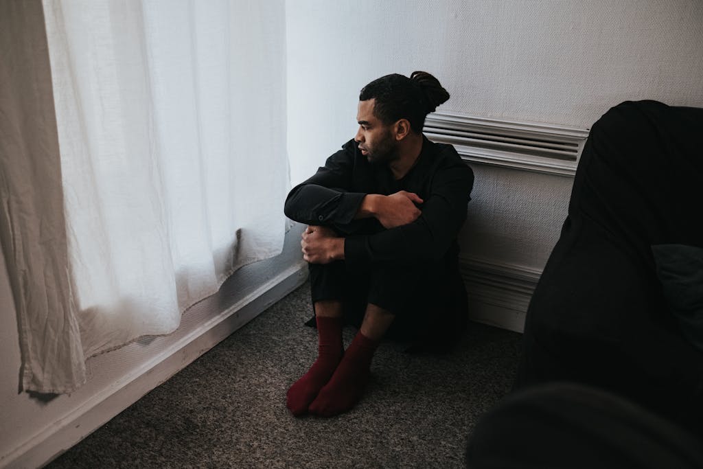 Man in Black Jacket and Red Pants Sitting on Floor