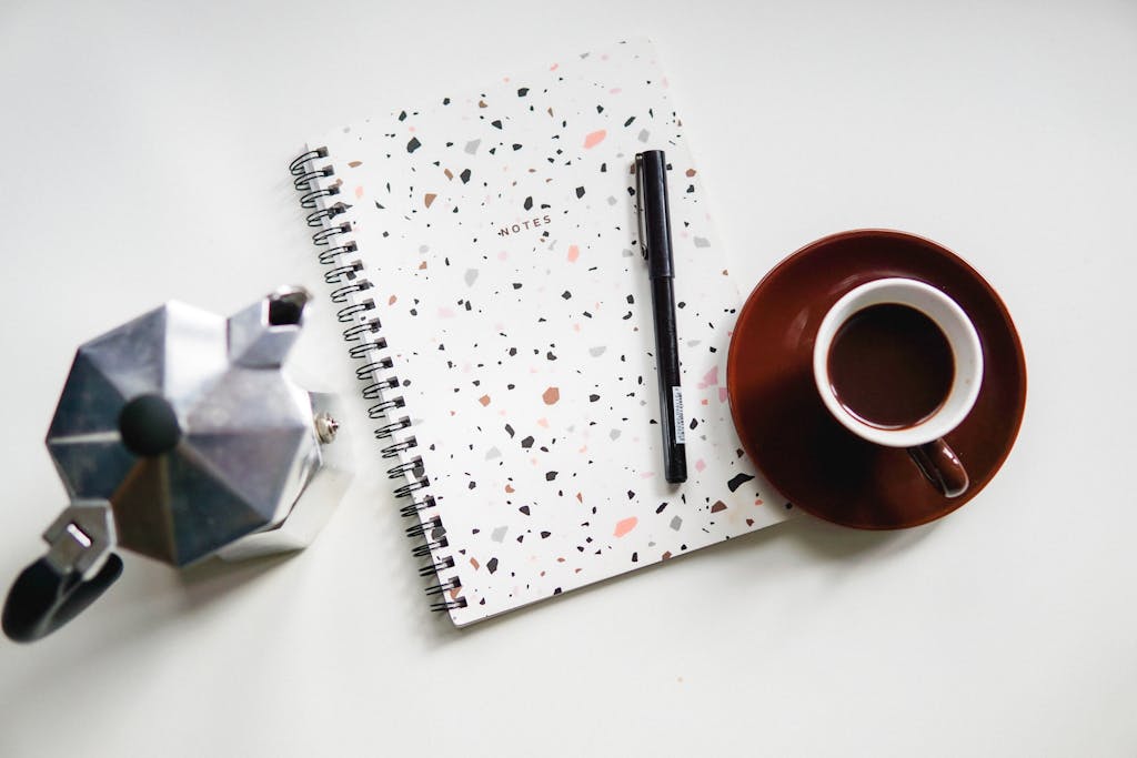 Notepad and pen placed on desk with coffee set