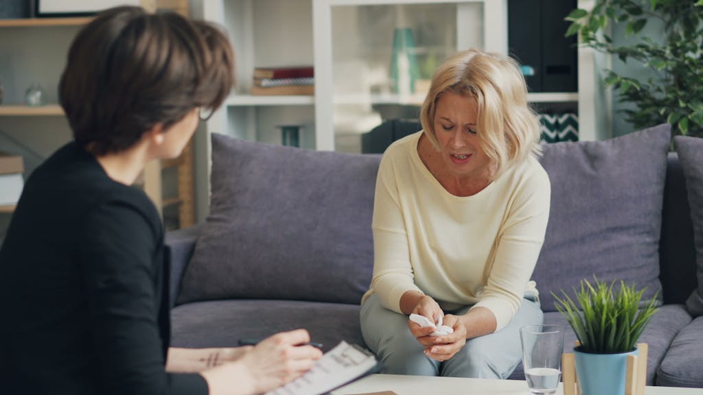 Two women sitting on a couch talking to each other